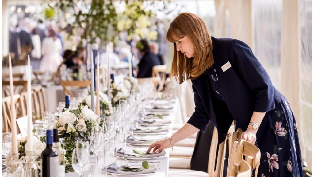 Wedding planner arranging guest accessories at a decorated wedding reception