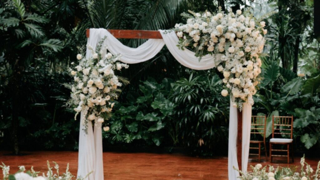 Floral wedding arch surrounded by tropical greenery