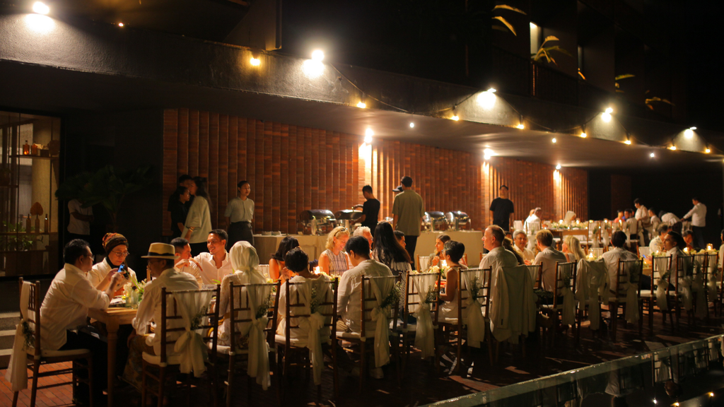 Wedding guests enjoying an intimate evening reception with warm lighting and long dining tables.